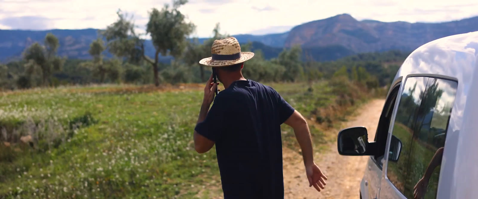 Xavier Vélez hablando por teléfono junto a una furgoneta, entre olivos y montañas